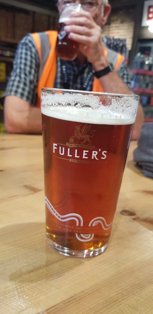 Pint of Fuller's Pride in a Fuller's pint glass with man drinking a pint